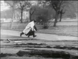 B/W 1956 PAN 2 men run quickly through park / one trips / Hungarian uprising Stock Footage