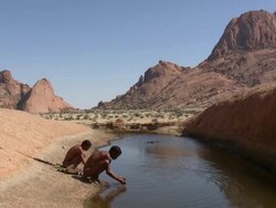 Bush people drinking at a water whole Stock Footage