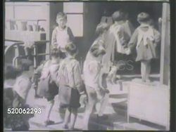 1942: JAPAN: SCHOOLS: VS Small children marching, entering school building. INT VS Japanese students in classroom learning from teacher, writing Kanji characters. Education, learning, writing Instructional Video