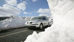 traffic passing large snowdrifts on the A591 road at Thirlmere in the Lake District, UK, following the unseasonal extreme weather events of late march 2013. Stock Footage