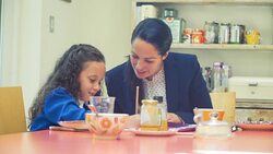 Working mother and daughter doing homework at breakfast table Stock Footage