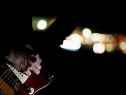 Picking guitar by the city road in night Stock Footage