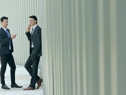 WS Two businessmen working on digital divices in front of a wall.  Stock Footage