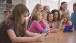 Elementary school aged children working on digital media tablets with teacher in classroom Stock Footage