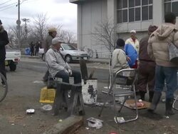 Destruction caused by tsunami after magnitude 9 Tohoku earthquake, north east Japan, March 2011. Elderly survirors sit around fire on street to keep warm after tsunami in Ishinomaki,  Miyagi Prefecture Stock Footage