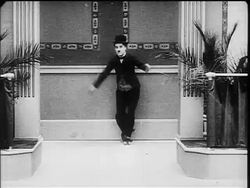 B/W 1916 Charlie Chaplin as Little Tramp roller skating on one foot Stock Footage