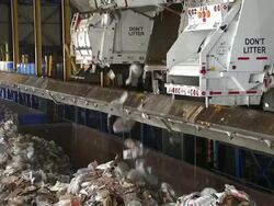 Dump trucks empty paper and paper products into roll-off containers at a recycling plant. Stock Footage