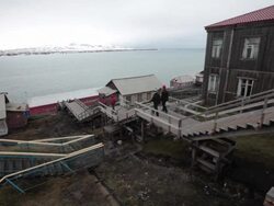 An old Russian houses in Barentsburg, a Russian mining settlement on Svalbard archipelago,with mountains covered by snow in the back Stock Footage
