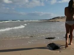 Teenage girl walks across beach with mp3 player, looks out Stock Footage