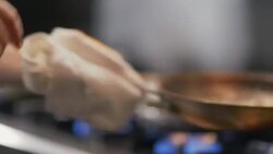 Restaurant cook flips vegetables in flaming skillet in restaurant kitchen Stock Footage