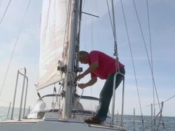 MS Pensioner ties down sail on his sailboat in sun on calm day / Wismar, Mecklenburg-Vorpommern, Germany Stock Footage