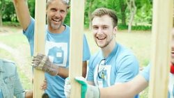 Portrait of smiling volunteers supporting construction frame Stock Footage