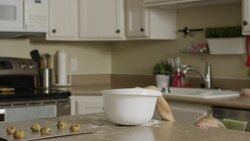 Medium panning shot of girl taking cookie dough from bowl in kitchen / Orem, Utah, United States Stock Footage