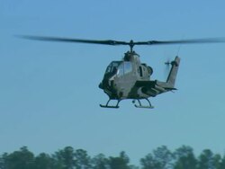 U.S. Army Cobra attack helicopter approaches airport taxiway and slows to a hover Stock Footage