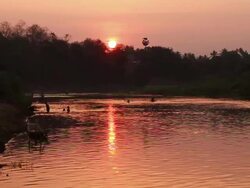 MS SLO MO Shot of reddish sun and river with silhouetted people bathing / Luang Prabang, Laos Stock Footage