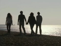 MS, Silhouettes of family with two children (10-11, 12-13) walking on Brighton beach at sunset, rear view, Brighton, Sussex, United Kingdom Stock Footage