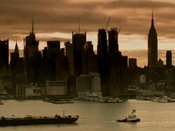 Tug boat pulling a barge down the hudson river with the empire state building, the chrysler building, the bank of america tower and other adjacent skyscrapers on the new york city skyline against the early morning sunrise Stock Footage
