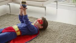 Superhero boy playing with helicopter in living room Stock Footage