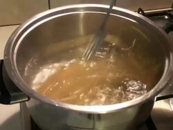 Woman's hand mixing spaghetti in the boiling water Stock Footage