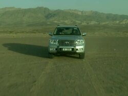 Vehicle driving in desert with mountain back drop, Jordan Stock Footage