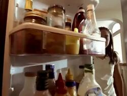 Low angle close up girl opening refrigerator / taking apple and biting it / closing refrigerator door Stock Footage