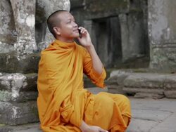 MS, PAN A Buddhist monk answers and talks on a mobile phone on the steps of an ancient temple in Angkor Wat / Siem Reap, Cambodia Stock Footage