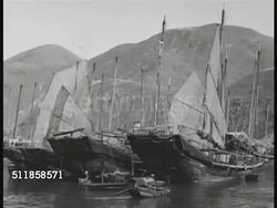 1950: THE FAR EAST: TU Commercial DC-3 flying over Chinese pagoda, traditional curled roof tips. Junks docked in harbor. Chinese residents walking w/ pole baskets past stacked Texaco oil drums. Male & female workers carrying cans on poles at dock. Instructional Video