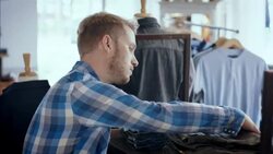 Modern shop worker counts stock and enters numbers on tablet in clothing store Stock Footage