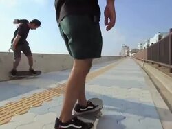 MS POV Two men's skateboarding on side walk beach area / Chatan, Okinawa, Japan Stock Footage