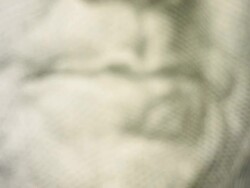 Pan up to a close up of Benjamin Franklin's face on the hundred dollar bill Stock Footage