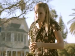 teenager playing brass saxophone practices her instrument in backyard of her home / Redlands, California, USA Stock Footage