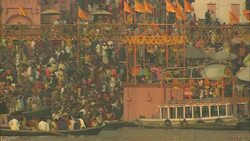 Boatmen carry standing passengers on the Ganges River as hundreds on shore wait their turns. Stock Footage