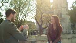 MEDIUM TILT DOWN woman poses for boyfriend taking photo on bridge in Paris Stock Footage