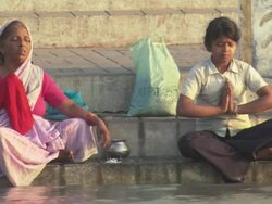 WS Elderly woman and young girl sitting with eyes closed and praying on stone embankment at the Ganges river / Kashi, Uttar Pradesh, India Stock Footage