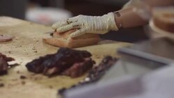 Skilled barbecue cook slices bread in restaurant kitchen Stock Footage
