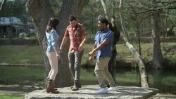 Group of friends dance on stone platform in scenic riverside park Stock Footage