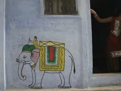 WS Young girl standing in doorway of house with elephant painted on wall / Varanasi, India Stock Footage