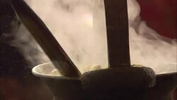 Ladles stir silk cocoons that boil in a pot while the silk threads are gently pulled away. Stock Footage
