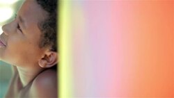 Brazilian boy turns and smiles at camera leaning against graffitied wall in Rio slum Stock Footage