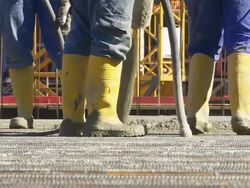 Workers Directing Concrete Onto The Construction Site Stock Footage