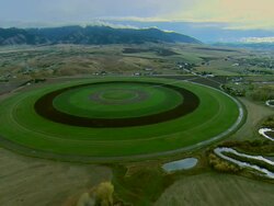 Aerial early morning sot of crop irrigation circle and mountains outside of Bozeman, MT Stock Footage