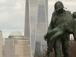 Statue in liberty state park depicting solders rescuing Holocaust victims from Germany in World War Two.  The skyscrapers of lower Manhattan are behind out of focus. Stock Footage