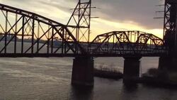 Aerial rising up from brush along the Delaware River to a truss bridge  Stock Footage