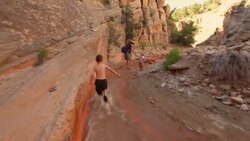 Follow young hiker boy as he runs through a canyon riverbed to catch up with his mother and younger sister Stock Footage
