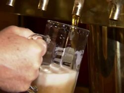 Close Up hand-held zoom-in-A hand holds a mug as the other hand fills it with beer from a tap.   Stock Footage