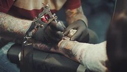 Tattoo artist tattooing young woman Stock Footage