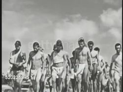 1945: OKINAWA, JAPAN: JUNE 22, 1945 SURRENDER: Japanese POW soldiers in little clothing walking in group.MS American flag lowering to half mast on pole. Pacific Theater, WWII, World War II. Instructional Video