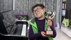 boy holding silver medal cup by the piano Stock Footage