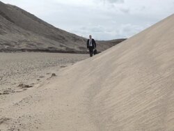 MS Young businessman dressed in  black suit walking on  sand dune in  rural area / Maple Grove, Minnesota, United States Stock Footage