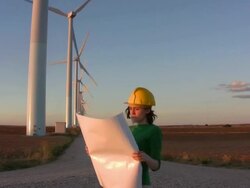 Female engineer looks at plans windmills background Stock Footage
